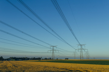 High voltage power lines and transmission towers in agricultural fields in Normandy, France....