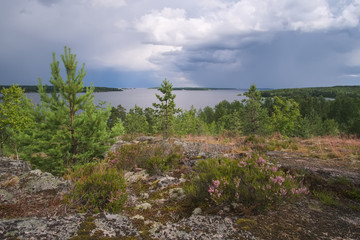 A landscape with a large lake from a high stone beach on a summer day with clouds. Ladoga Lake, the Leningrad Region