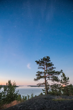 Night landscape with stars over a large lake on a high stone lake shore. Ladoga Lake, the Leningrad Region