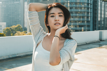 Young asian woman posing on rooftop level in cityscape  wearing casual clothes