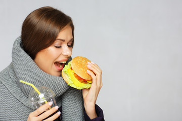 Portrait of woman wearing warm scarf eating fast food.