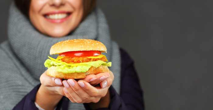 Smiling woman holding burger in two hands.