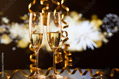 Two Champagne Glasses With Ribbons Against Holiday Lights And