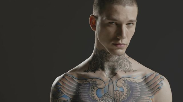 Handsome sexy young man stylish with tattoo on his neck, torso and hand - middle shot portrait studio - Prores - cinematic fashion lighting