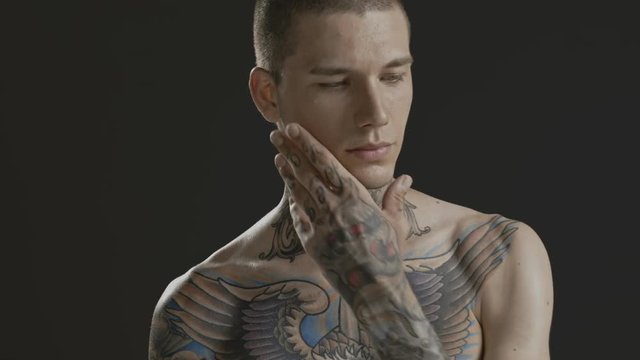 Handsome sexy young man stylish with tattoo on his neck, torso and hand - middle shot portrait studio - Prores - cinematic fashion lighting
