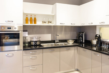 Modern kitchen furniture with contemporary kitchenware like hood, black induction stove and oven in...