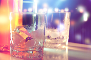 ice in glass in nightlife with colourful blurred background.