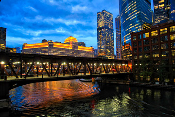 Chicago's illuminated night lights over Chicago River and at Merchandise Mart during rush hour.