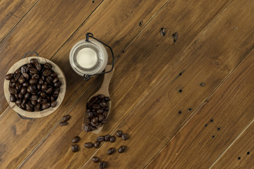 Coffee bean grain ,bottle of milk and sack fabrice board on brown wood table background , include copyspace for add text or graphic in advertise or marketing content
