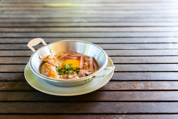 Fried egg with minced pork, sliced ham and sausage in aluminium pan on wooden table. Breakfast fried egg.