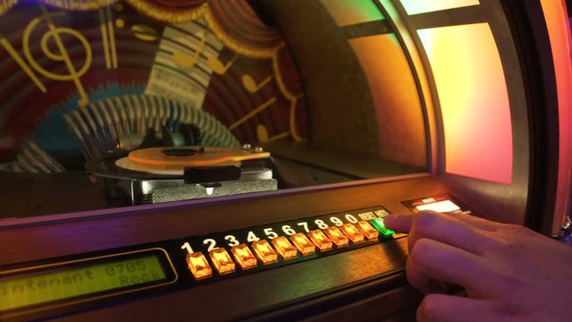 Male hand pushing buttons to play song on old musical box, selecting records