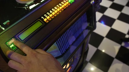 Male bar visitor choosing song to play on jukebox with great variety of disks