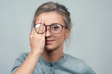 Tired woman in eyeglasses, covering eyes with hands