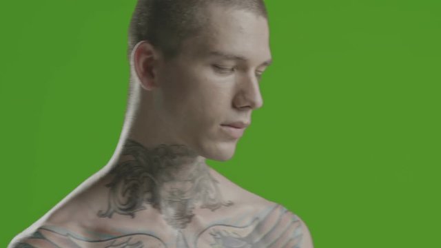 Handsome sexy young man stylish with tattoo on his neck, torso and hand - middle shot portrait studio - greenscreen Prores - cinematic lighting