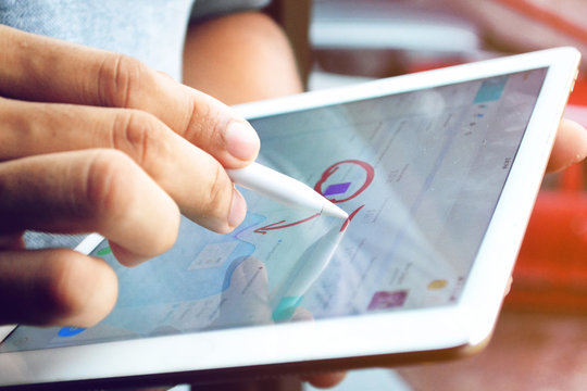 Man Analysing And Interpreting Graphs And Charts On His IPad Tablet