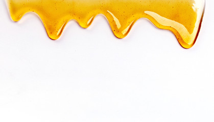 Dripping honey seamlessly repeatable from the top over white with copyspace. - obrazy, fototapety, plakaty