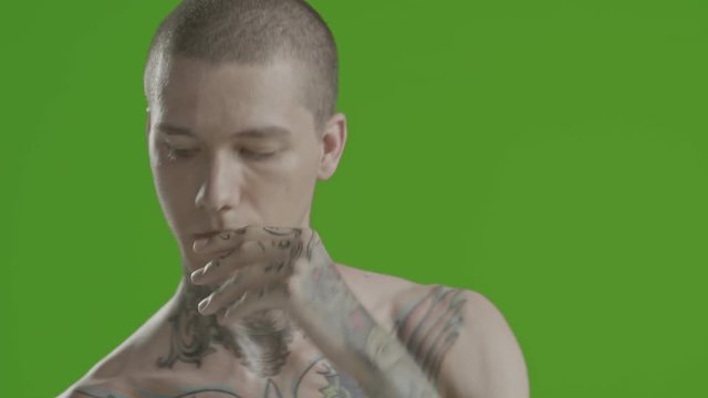 Handsome sexy young man stylish with tattoo on his neck, torso and hand - middle shot portrait studio - greenscreen Prores - cinematic lighting