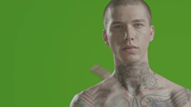 Handsome sexy young man stylish with tattoo on his neck, torso and hand - middle shot portrait studio - greenscreen Prores - cinematic lighting