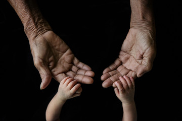 Hand of a young baby touching old hand of the elderly (Soft focus and blurry)