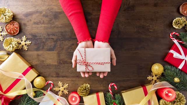 Hands showing Christmas gift box on wood table