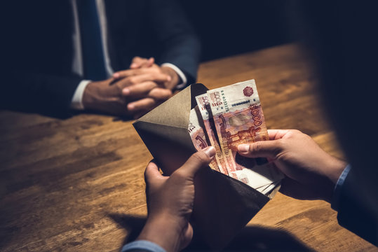 Businssman counting rubles in envelope in dark room.
