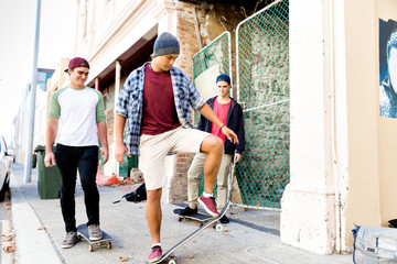 Fototapeta premium Teenage friends walking at the street with skateboards