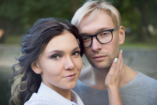 Brunette girl holding gently by the neck man blonde close-up