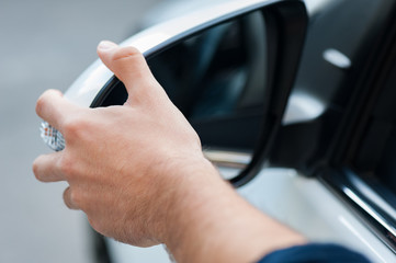 Young human hand is preparing or correct car mirror for the trip or travel from car window.