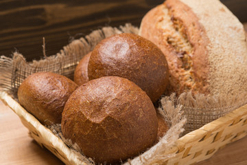 assortment of fresh bread in a basket on a wooden table, composition with additional accessories