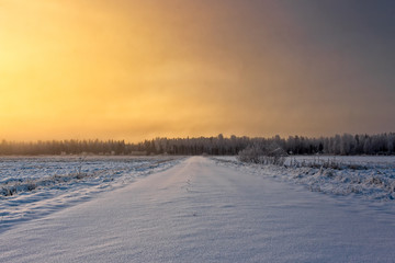 Fototapeta na wymiar Snowy Road In The Winter Sunrise
