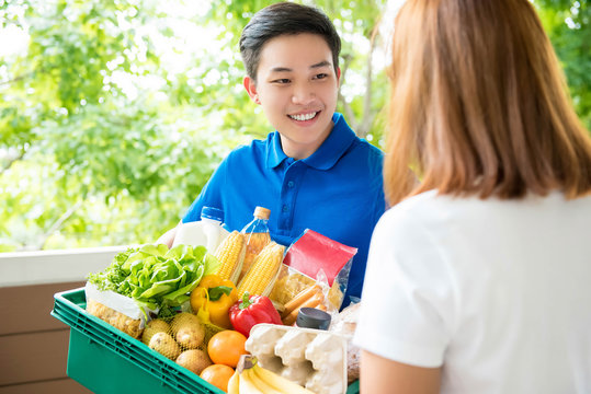 Asian Delivery Man Handing Food Over To A Customer At Her Residence