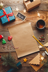 Beautiful Christmas background with a new year décor, a sheet of old paper, garland and gifts, gingerbread and a Cup of tea on a wooden background. Merry Christmas postcard.