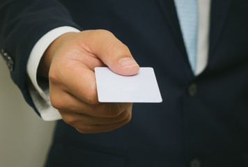 Business man handing a blank business card over white background