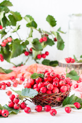 Berries and leaves of hawthorn in a wicker basket on a wooden table