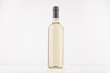 Transparent wine bottle with white wine on white wooden board, mock up. Template for advertising, design, branding identity.