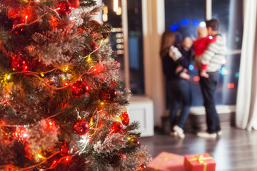 Christmas 2018. Happy family with presents and gifts near a big window, looking to magic light in night Xmas tree interior