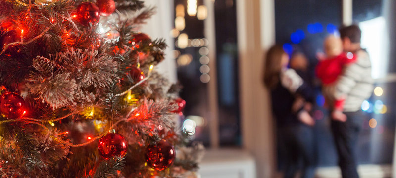 Christmas Scene With Happy Family Of Four, Tree Gifts And Window In Blurred Bokeh Background, Copy Space