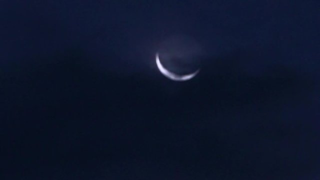 A view of a crescent moon on a cloudy night.