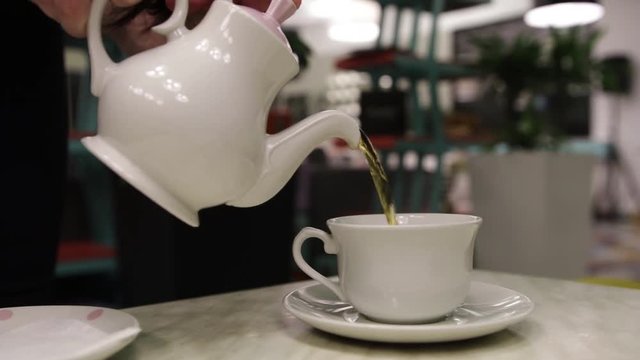 from a teapot pour tea in a mug