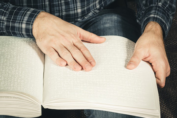 The blind man was reading a book written on Braille. Touch your finger on the braille code. A book with Braille text