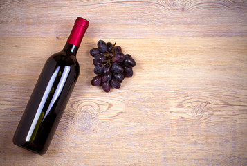 Bottle of wine on rustic wooden background, copy space, top view, horizontal. Red wine