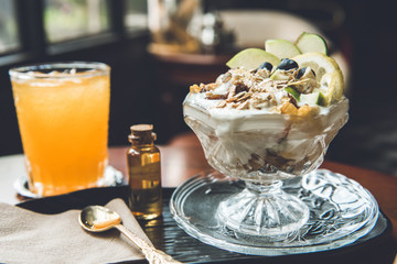 Appetizing healthy yogurt fruit salad topped with oat cereal for breakfast