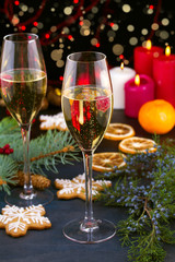 Champagne glasses in holiday setting. Christmas and New Year celebration with champagne. Christmas holiday decorated table with white sparkling wine, vertical