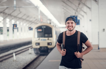 Young traveler walking with backpack on train staition and waiting train