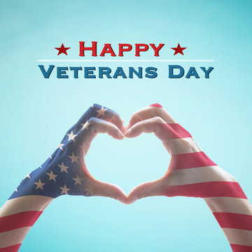 USA Happy veterans day with United Stated of America flag pattern on people's hands in heart shape on blue sky greeting announcement honoring all veterans who served American country