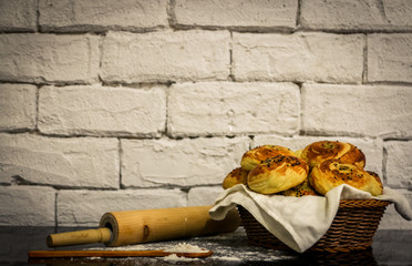 Fresh homemade buns on basket with rustic white brick background.