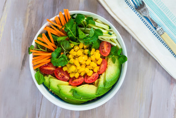 Vegan Buddha bowl with quinoa, avocado, carrots, sweetcorn, tomatoes and courgette