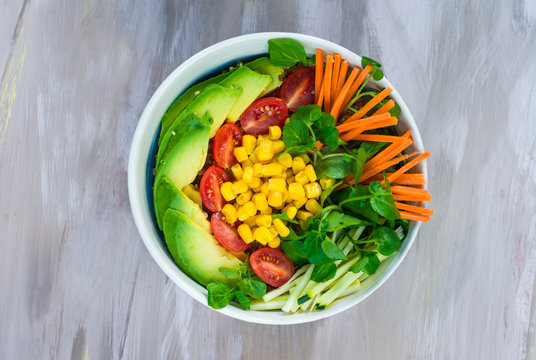 Vegan Buddha bowl with quinoa, avocado, carrots, sweetcorn, tomatoes and courgette