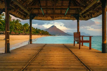 Foto op Aluminium Wonderful view across the pier, on the left the tropical beach and in the background a beautiful mountain illuminated by red during sunset, Mauritius   © robertobinetti70