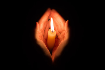 hands holding a burning candle in dark like a heart